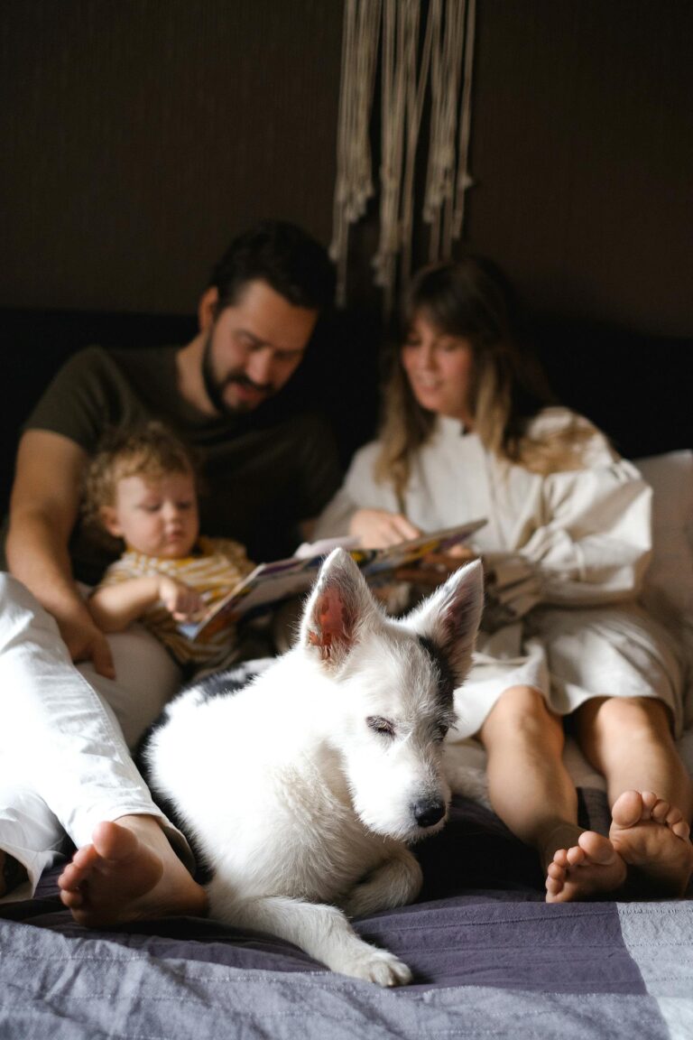 A family spending quality time together reading on the bed with their pet dog.
