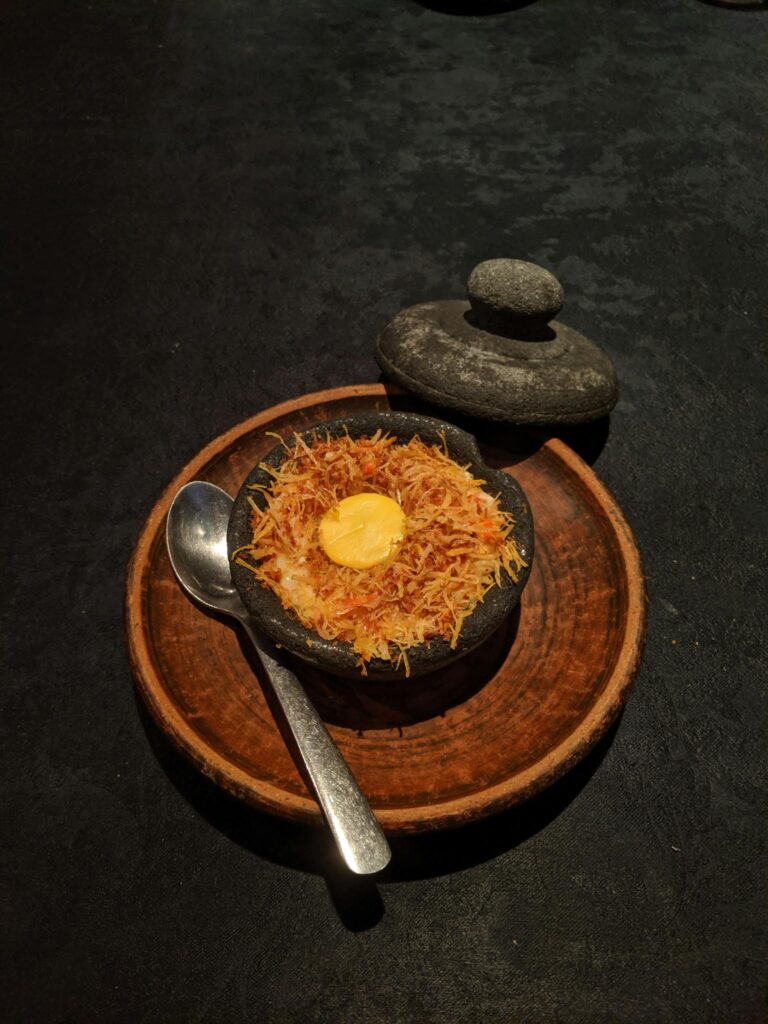 Elegant presentation of Indonesian dish in a traditional stone pot.