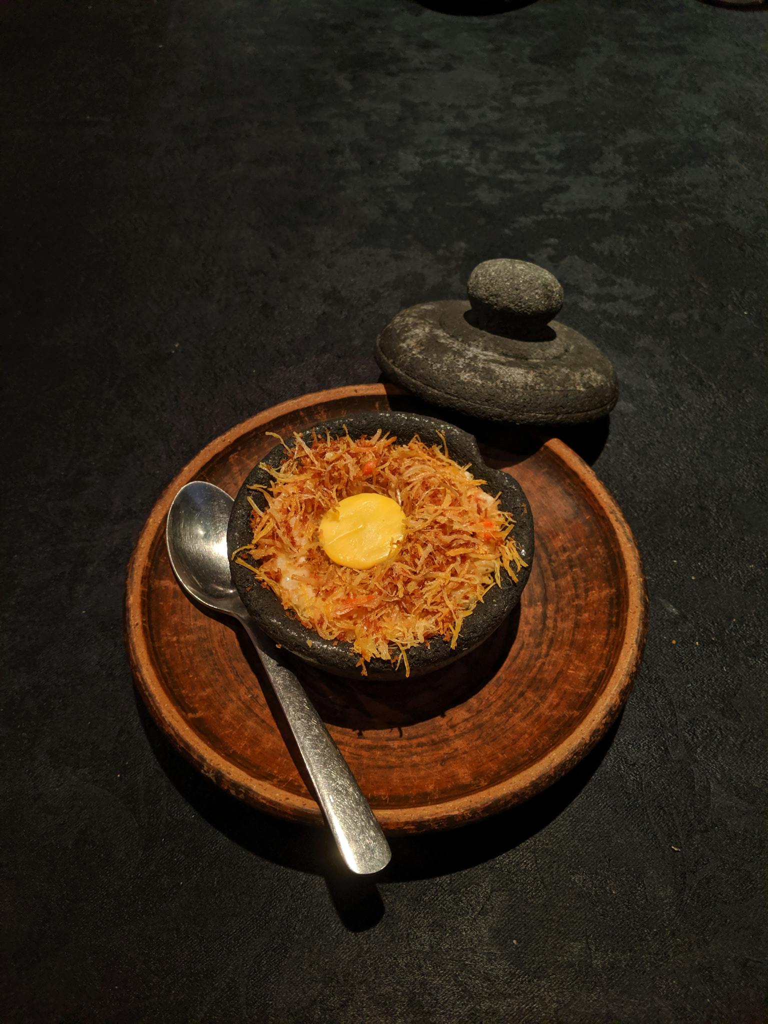 Elegant presentation of Indonesian dish in a traditional stone pot.