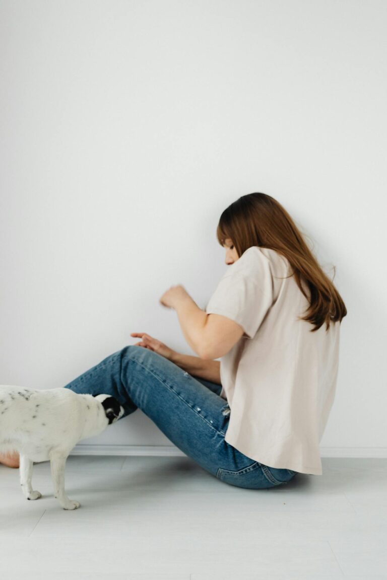 Young woman interacting with a small dog by the wall, depicting emotion.